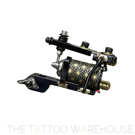 Close up of the eruhiga grand line tattoo machine. it is rotary powered with a distinctive armature bar and back spring similar to a coil. Blue and black in colour with geometric patterns on the motor.